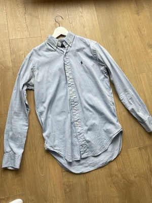 Ljusblå skjorta från Ralph Lauren - Säljer en fin Ralph Lauren skjorta i storlek S. Den är i en fin ljusblå färg. Skjortan är i fint skick men har ett litet märke på armbågen och ett litet på magen precis som man ser på sista bilderna Priset ej hugget i sten. Hör av dig vid frågor😊