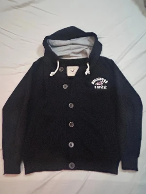 Svart Hollister Cardigan - Skick 8,5/10 syns på bild / Storlek S passar även liten M / Perfekt nu när vädret börjar bli varmare och man vill ha en schysst stilren Cardigan / Bara att höra av dig vid frågor och intresse! 