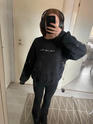 Svart sweatshirt med broderad text - En svart oversized sweatshirt med vit broderad text på bröstet. Tröjan har rund halsringning och långa ärmar med ribbade muddar. Ingen huva. Passar perfekt till ett avslappnat streetwear-look. Märke och material framgår ej.