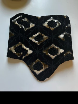 Korsett / Corset - Korsett med dragkedja. Svart semi glansigt tyg med glansigt creme färgat mönster. Raklång och öppen (som visat på sista bilden) är den ca 84 cm i omkrets (runt midjan/ revbenen).