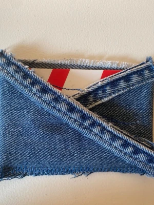 Plånbok i denimtyg med råa kanter - Unik plånbok sydd av blått denimtyg med synliga råa kanter och kontrastsömmar. Plånboken har ett kuvertformat lock och är perfekt för dig som gillar en kreativ och personlig stil. Passar för kort och sedlar. Plånboken är gjord av vårat uf företag deni_mdesigm.