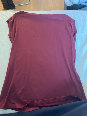 Vinröd ärmlös topp från 157 - Enkel vinröd ärmlös topp från 157 i mjuk bomull. Modellen är rak och passar perfekt till jeans eller kjol. Snygg att bära som den är eller under en jacka. Färgen är djup vinröd och materialet känns skönt mot huden.