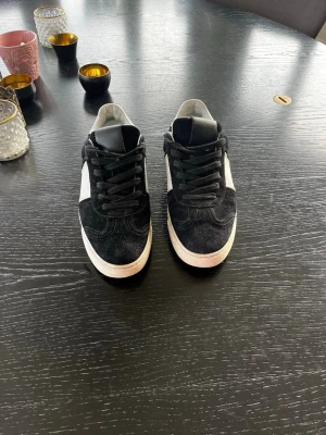 Valentino garavani fly crew  - Snygga svarta Valentino sneakers med vit sula och vita detaljer på sidorna. Skorna har svart mockaliknande material, svarta skosnören och en klassisk låg siluett. Alla nitar finns kvar. 