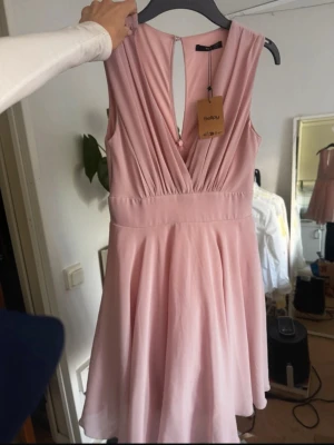 Ljusrosa omlottklänning från TFNC London - Supersöt ljusrosa klänning från TFNC London. Klänningen har en omlott-detalj och v-ringning som gör sig väldigt fint på kroppen. Köpt på Sellpy i ny-skick och är aldrig använd varken av mig eller tidigare ägaren