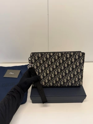 DlOR NAVY BLUE POUCH - Säljer denna klassiska väska i det ikoniska Oblique-mönstret. Väskan är både stilren och praktisk,  Detaljer: Modell: Oblique Canvas Clutch (Navy Blue/Beige) Skick: Ny skick (se bilder för detaljer).  Tillbehör: Kommer med originalbox, dustbag och veriferingskort. En tidlös accessoar som aldrig går ur tiden. Passa på att fynda en lyxig klassiker!  Skickas spårbart och försäkrat. Tveka inte att skicka ett meddelande om du har frågor eller vill ha fler bilder!