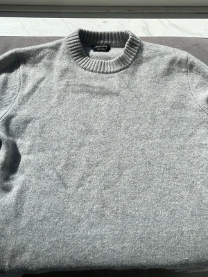 Ljusgrå stickad tröja Massimo Dutti i storlek M - Ljusgrå stickad tröja från Moassimo Dutti i merino ull. Det finns ett litet hål vid sidan av tröjan men det är inget som syns vid användningen.Tröjan är knappt använd och i ett bra skick, perfekt för kyliga dagar😃Priset är inte spikat och går att ändra vid en snabb affär, hör av er om ni har frågor.