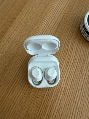 Vita Samsung Galaxy Buds med laddetui - Säljer ett par trådlösa Samsung Galaxy Buds i snygg vit färg. De kommer med ett matchande laddetui i plast som är smidigt att ta med sig. Perfekta för musik, poddar och samtal när du är på språng.