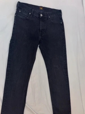 Svarta skinny jeans från Lee - Snygga svarta skinny jeans från Lee med klassisk femficksdesign och dragkedjegylf. Jeansen har en smal passform och är tillverkade i stretchigt denimtyg för extra komfort. Perfekta för en trendig och avslappnad look. Storlek 30-30