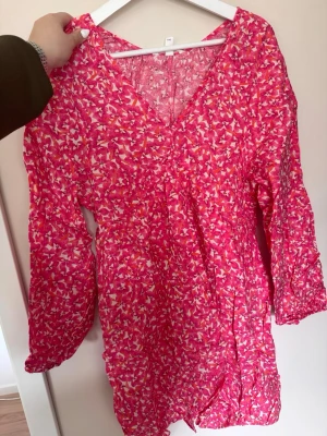 Blommig rosa klänning H&M - Supersöt klänning från H&M i rosa med blommigt mönster. Klänningen har v-ringning, långa ärmar med resår och en lätt volangig kjol. Perfekt för vår och sommar, tillverkad i ett tunt och luftigt material. Kom med prisförslag! 