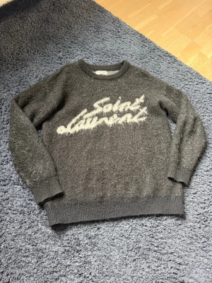 Saint Laurent Tröja - Stilren Yves Saint Laurent tröja. Storlek M utan teckan på användning. Pris satt på 2999kr för tillfället då tröjmodellen inte produceras längre och orignalpriset låg på runt 11 000kr. Tröjan är intröe för varm vilket gör den till ett perfekt alternativ för dig som vill känna dig extra fräsch i sommar.
