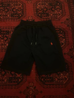 Svarta shorts från Polo Ralph Lauren - Svarta shorts från Polo Ralph Lauren med elastisk midja och snörning. Storlek M men skulle säga att det passar bättre om man har EU S.