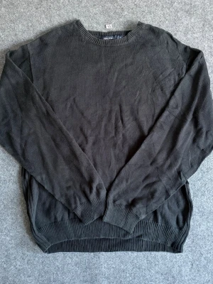 Svart stickad tröja från Nautica - Klassisk svart stickad tröja från Nautica i storlek XL. Tröjan har rund halsringning, långa ärmar och ribbstickade muddar vid ärmslut och nederkant. Perfekt för en stilren och enkel look.