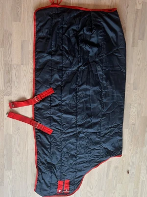 Häst täcke Mio - Fint täcke från Mio som är mörkblå med röd kant, varsamt använd, tvättad och har tidigare används till islandshäst 💕💕
