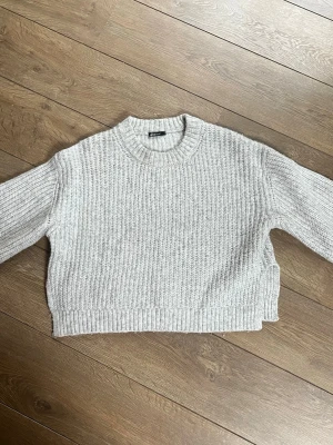 Ljusgrå cropped stickad tröja - Säljer en ljusgrå cropped stickad tröjafrån Ginatricot med grov ribbstickning och rund hals. Tröjan har långa ärmar och breda muddar vid ärmslut och nederkant. Fråga gärna vid frågor💕