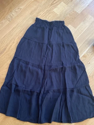 Svart långtjol från H&M - Säljer ett par mörkblå linnebyxor från H&M med bred, smockad midja för extra komfort. Byxorna är tillverkade i ett luftigt linnematerial och har en avslappnad passform som passar perfekt till sommaren.