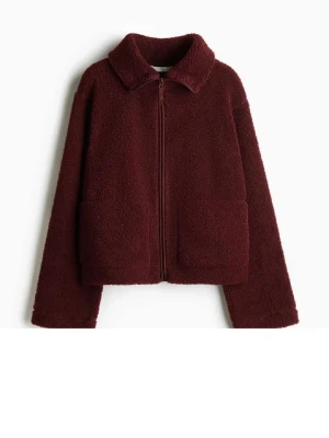 Vinröd teddyjacka med dragkedja - Mysig vinröd teddyjacka med dragkedja framtill och två stora fickor. Jackan har en klassisk krage och är tillverkad i mjukt, fluffigt teddy-material som håller dig varm. Perfekt för dig som gillar en avslappnad och trendig stil.