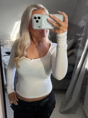 Vit långärmad croppad topp - Snygg vit långärmad topp med croppad passform och lätt u ringad framtill!