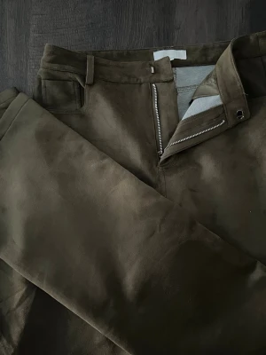 Mockabyxor – NA-KD x Lovisa Wallin - Eleganta gröna mockabyxor från NA-KD i samarbete med Lovisa Wallin. Byxorna har en stilren och smickrande passform med exklusiv känsla. Perfekta till både vardag och fest – lika snygga med stickat som med klackar och kavaj.  ✨ Endast använda en gång – mycket fint skick 📏 Storlek 38 🎨 Färg: grön 👖 Material: mockaimitation 💰 Nypris 799 kr  Säljes eftersom de tyvärr inte kom till användning. Ett riktigt fint plagg från en populär kollektion. 