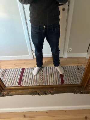 Replay jeans - Säljer ett par mörkblå slim fit jeans från replay med klassisk femficksdesign och snygga kontrastsömmar. Jeansen har normal midja och är tillverkade i stretchigt denim för extra komfort. Perfekta för en avslappnad och trendig look.