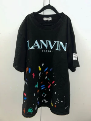 Svart Lanvin t-shirt med färgstänk - Snygg svart t-shirt från Lanvin med stort tryck framtill och färgstänk i flera färger. Den är i storlek S och pris kan diskuteras!