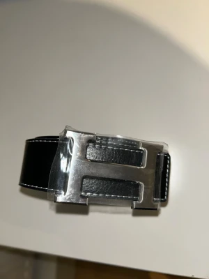 H3rm3s bälte med H-logga - Stilrent svart skärp med H-logga. Helt ny. Storlek 110cm. 