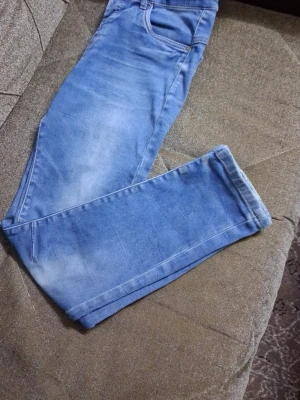 Ljusblå raka jeans - Säljer ett par ljusblå jeans med raka ben och klassisk femficksdesign. Jeansen har en snygg tvättad look med ljusa partier och är tillverkade i ett mjukt denimtyg. Perfekta för en avslappnad stil och passar till det mesta.