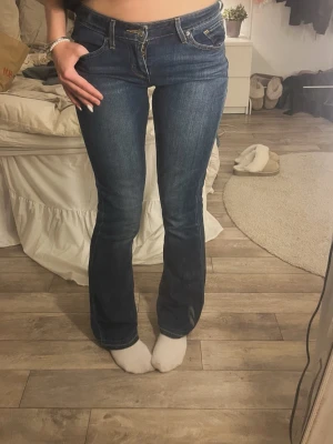 Mörkblå bootcut jeans från Levi's - Säljer ett par mörkblå bootcut jeans från Levi's med klassiska fem fickor och snygga kontrastsömmar. Jeansen har en något utsvängd passform nedtill och är tillverkade i slitstark denim. Perfekta för dig som gillar en tidlös och avslappnad stil. Är uppsprättade längst ner