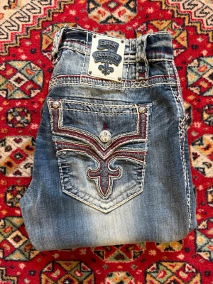 Rock revival jeans - Rock revival jeans med snyggaste faden och snyggaste fickorna. bra skick förutom en bältesögla som har blivit klippt av på mitten men som går att fixa enkelt. Storlek W32. Mått: 43 cm midja, 111 cm längd, 23 cm benöppning