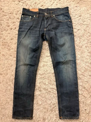 Mörkblå raka jeans med kontrastsömmar - Snygga mörkblå jeans med raka ben och klassisk femficksmodell. Jeansen har kontrastsömmar och metallknappar för en tidlös look. Materialet är denim i bomull och passformen är normal. Perfekta till en avslappnad stil.