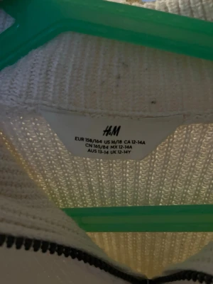 Vit ribbstickad tröja från H&M - Säljer en vit ribbstickad tröja från H&M med hög krage och dragkedja framtill. Tröjan har långa ärmar och är tillverkad i ett mjukt stickat material som passar perfekt för kyligare dagar.