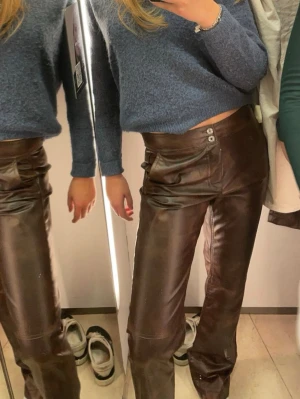 Bruna skinnbyxor med raka ben - Säljer ett par bruna skinnbyxor med raka ben och dubbla knappar i midjan. Byxorna har en cool fickdetalj framtill och sitter snyggt på höften. 