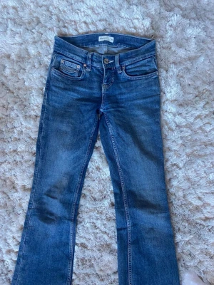 Blå bootcut jeans  - Snygga blå bootcut jeans med klassisk femficksdesign och normalhög midja. Jeansen har en lätt tvättad look och är tillverkade i mjukt denimtyg med stretch för extra komfort. Perfekta för en avslappnad och trendig stil.