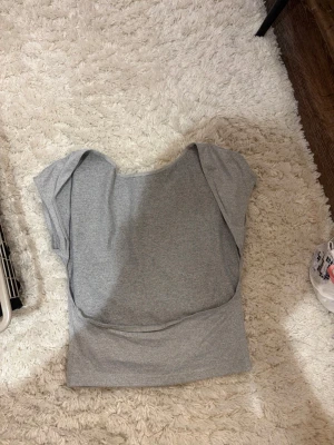 Grå croppad topp med kort ärm - Snygg grå croppad topp i mjukt material med korta ärmar.  Perfekt att matcha med jeans eller kjol för en avslappnad look. Även öppen rygg