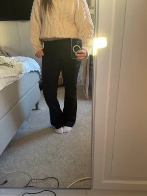 Svarta kostymbyxor med raka ben - Snygga svarta bortvittring kostymbyxor med klassisk passform. Byxorna har diskreta fickor i sidorna och hällor för skärp i midjan. Perfekta för en clean och stilren look. Materialet ser ut att vara en mjuk och följsam mix, troligen polyester eller viskos.