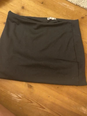 Svart kortkjol i bomull - En enkel svart kortkjol i mjukt bomullsmaterial. Kjolen har en rak passform och är perfekt att matcha med olika toppar. Klassisk och stilren design utan synliga detaljer.