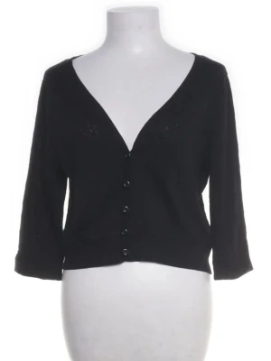 Svart kort kofta  - Stilren svart kofta med v-ringning och knappar framtill. Modellen är kortare och har trekvartsärmar, perfekt att slänga över en topp. Enkel och klassisk design som passar till det mesta.