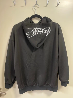 Svart hoodie  - Säljer en svart hoodie med snygg skrivstil på luvan.