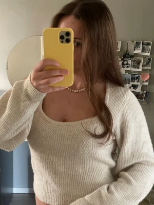 Ljusbeige stickad tröja med uringning - Säljer en ljusbeige stickad tröja med fyrkantig halsringning och långa ärmar. Tröjan har ribbstickad struktur och är lite kortare i modellen, perfekt för att matcha med jeans. Materialet är mjukt och mysigt! 