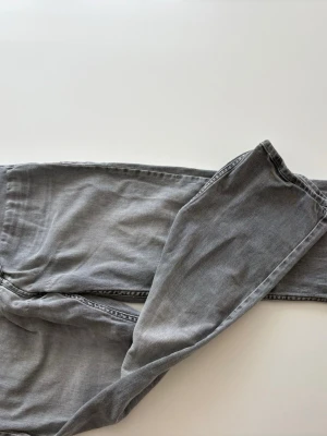 Grå jeans från Replay - Snygga grå jeans från Replay med klassisk femficksdesign och raka ben. Jeansen har en cool tvättad look och detaljerade bakfickor med broderi. Perfekta för dig som gillar en avslappnad men trendig stil.