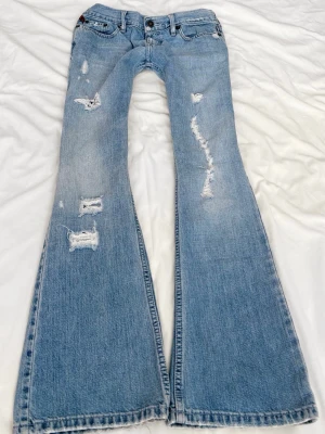 Ljusblå slitna superlågmidjade bootcut jeans - Sååå sjukt snygga superlågmidjade vintage bootcut jeans från Hollister!! 😩😩🙏🏼💓säljer eftersom de inte passar därför har jag heller ingen bild på! 💓 Midjemått: 36 cm Innebenslängd: 78 cm 