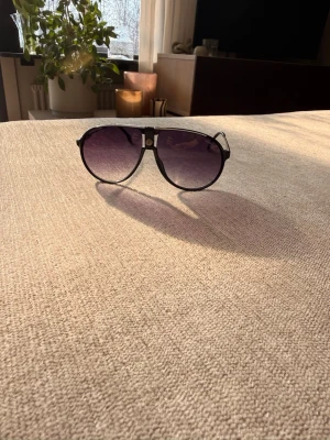 Svarta carrera solglasögon  - Snygga svarta Carrera solglasögon med metallbågar och mörka tonade glas. Klassisk och tidlös design som passar till alla outfits. Perfekta för soliga dagar och ger en cool vibe.