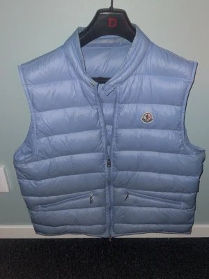 Moncler väst  - Snygg ljusblå dunväst från Moncler i storlek 4. Motsvarar L och passar som L ska göra äkta med måste bli av med den av privata skäl priset kan diskuteras vid smidig och trevlig affär mvh Axel 