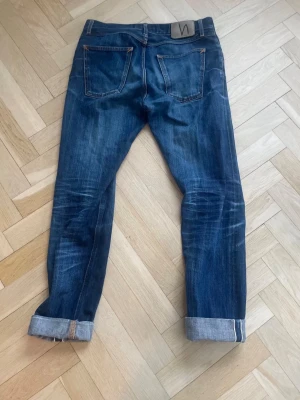 Nudie jeans- Dry Selvedge (Steady Eddy) - Nudie Jeans Steady Eddie – Dry Selvedge Denim. Snygg wash som blivit bättre med användning. Använda ett tag men fortfarande i bra skick. Klassisk selvedge denim med hög kvalitet.  Storlek 31/34 men sitter mer som 31/32 enligt mig. Nypris cirka 2500 kr.  Kan skickas eller mötas upp. Bra pris vid snabb affär.