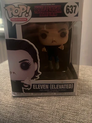 Funko Pop Eleven Elevated Stranger Things - Säljer en Funko Pop vinylfigur av Eleven (Elevated) från Stranger Things, nummer 637. Figuren är i sin originalförpackning och har detaljer som mörkt hår, svarta kläder och svävande pose. Perfekt för samlare eller fans av serien.