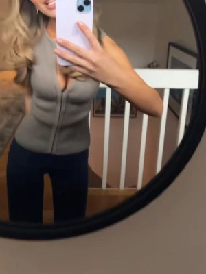 Beige ribbad polotopp med dragkedja💖💖 - Snygg beige ribbad polotopp med dragkedja framtill och djup v-ringning. Toppen är figurnära och har ärmlös design, perfekt för att styla med jeans eller kjol. Enkel men trendig look som passar till många outfits.