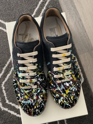 Maison Margiela gats  - Säljer ett par riktigt snygga skor från Maison Margiela i storlek 44 med paint splatter designen. Dessa skor är perfekta för dig som vill ha något Riktigt snyggt men även unikt.