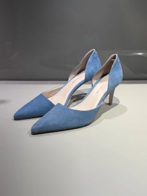 Ljusblåa pumps i mocka - Snygga ljusblå klackar med spetsig tå och mellanhög klack. Skorna är tillverkade i mjuk mocka. Aldrig använda då de varit för stora för mig!