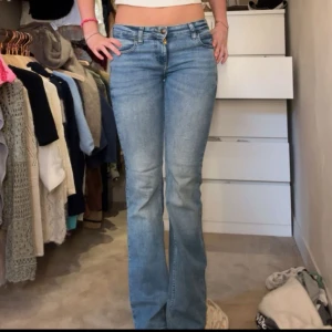 Blå bootcut jeans från Lee - Säljer ett par klassiska blå bootcut jeans från Lee. Jeansen har hög midja, fem fickor och stängs med knapp och dragkedja. Tillverkade i slitstark denim med snygg tvättad look. Perfekta för en avslappnad och trendig stil. Lågmidjade trendiga och i bra kvalitet.