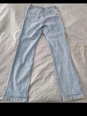 Ljusblå raka jeans - Säljer ett par ljusblå jeans med rak passform och klassiska fem fickor. Jeansen har normal midja och är tillverkade i denim. Perfekt för dig som gillar en avslappnad och tidlös stil.