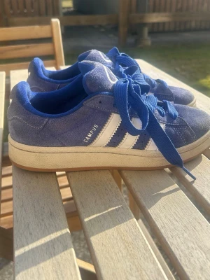 Blå Adidas Campus sneakers - Säljer mina blå Adidas Campus sneakers i mocka med vita klassiska stripes på sidorna och blå snören💙